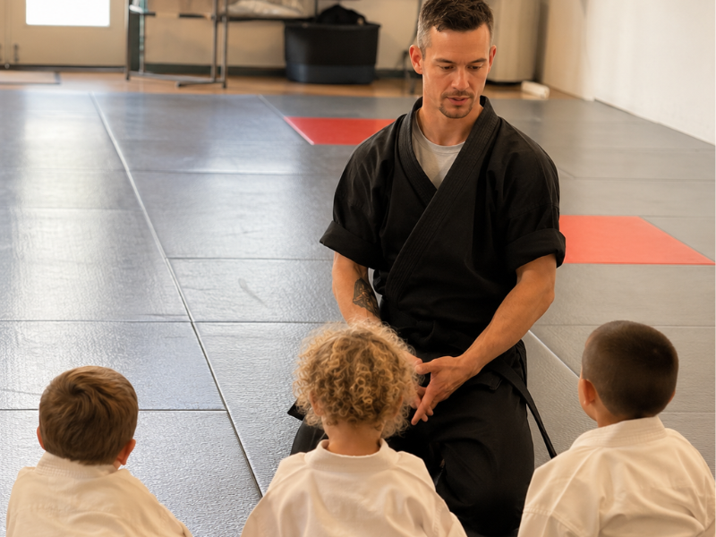 Instructor teaching young martial arts students on the mat